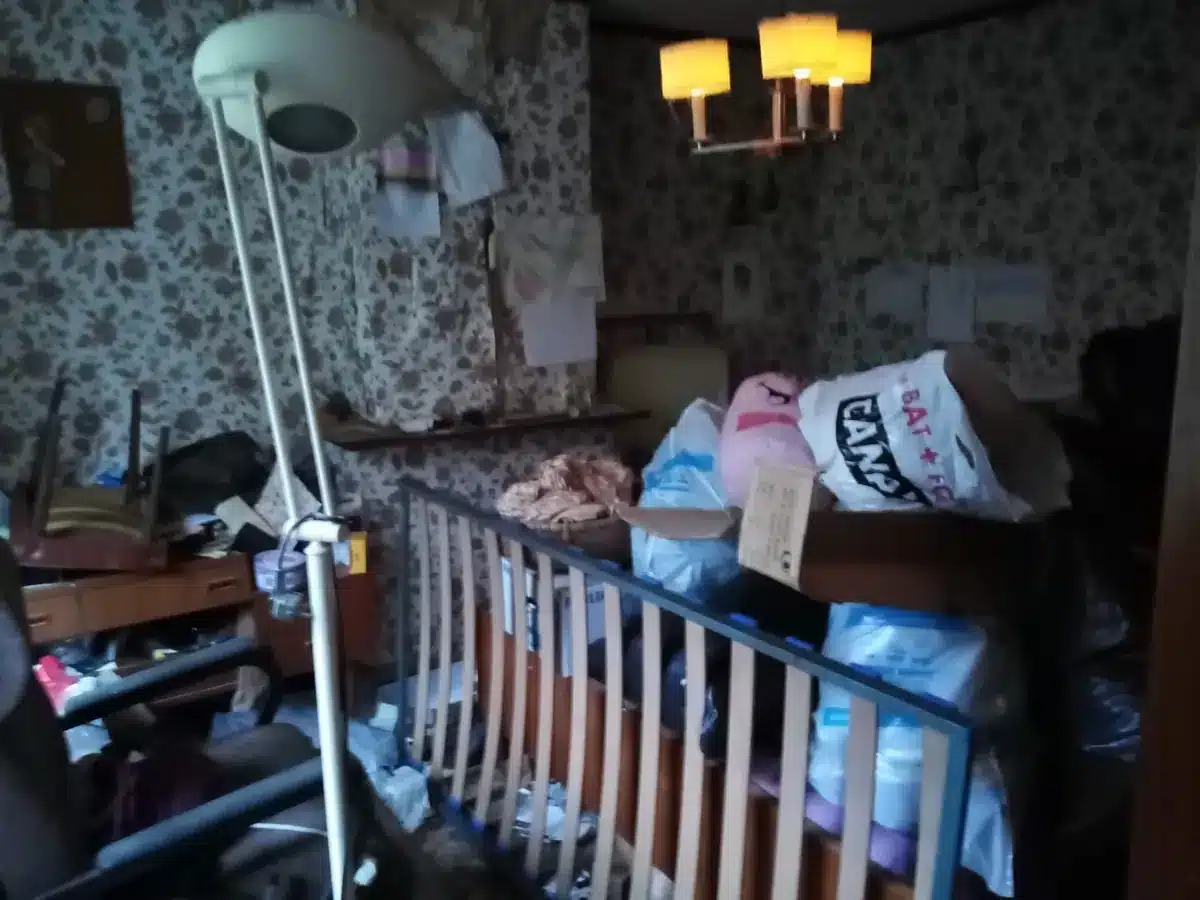 Chambre au papier peint fleuri encombrée de sacs et de meubles avant un vide-maison à Rixensart