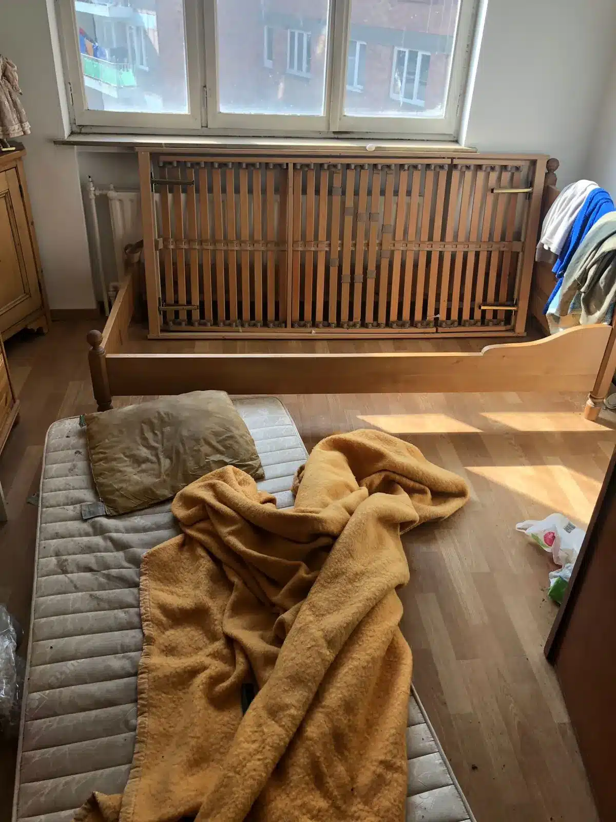 Chambre encombrée de linge et d'objets dans un appartement à Ixelles avant le tri