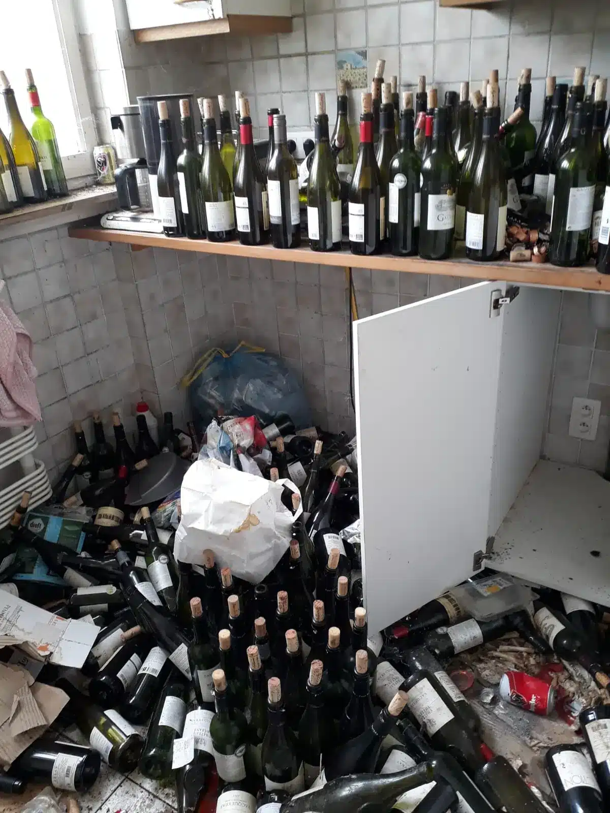 Cuisine d'un appartement à Ixelles envahie de bouteilles et de déchets