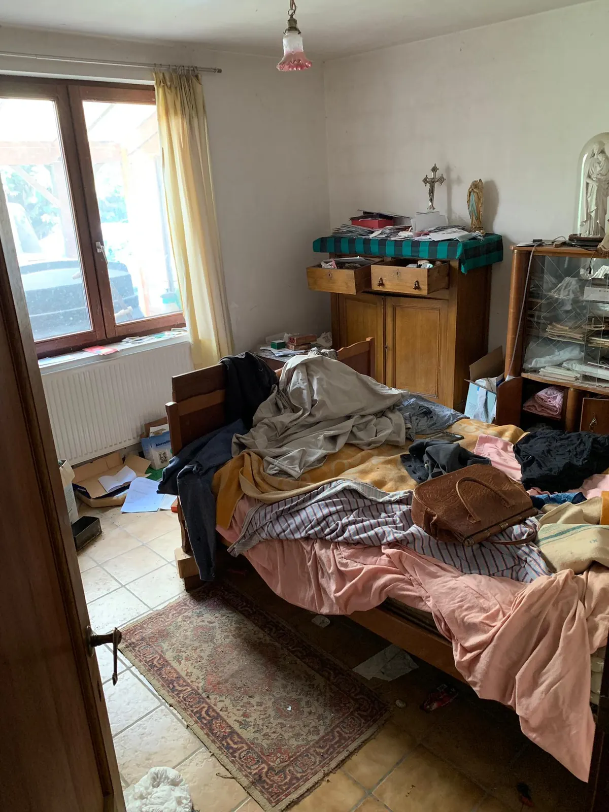 Chambre encombrée de vêtements et d'objets sur le lit avant un vide-maison à Nivelles