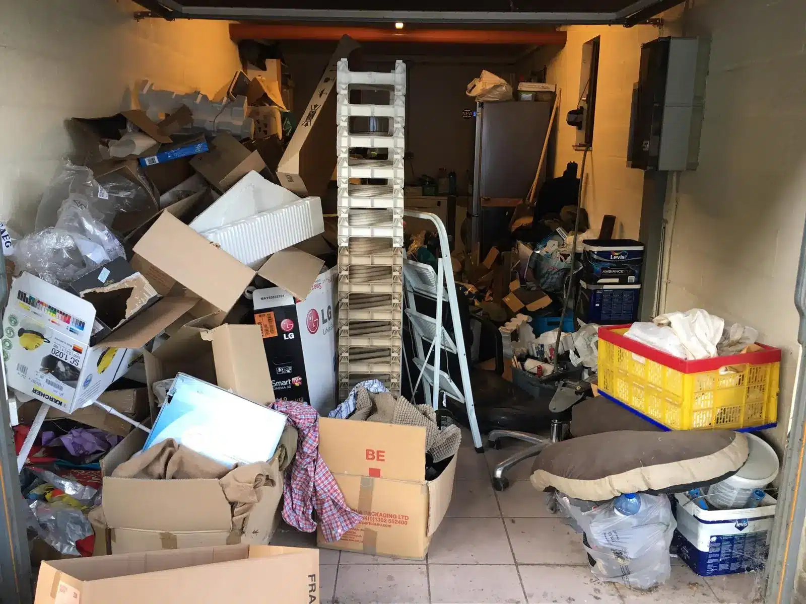 Garage rempli de cartons, d'objets et de déchets dans une maison à Obourg